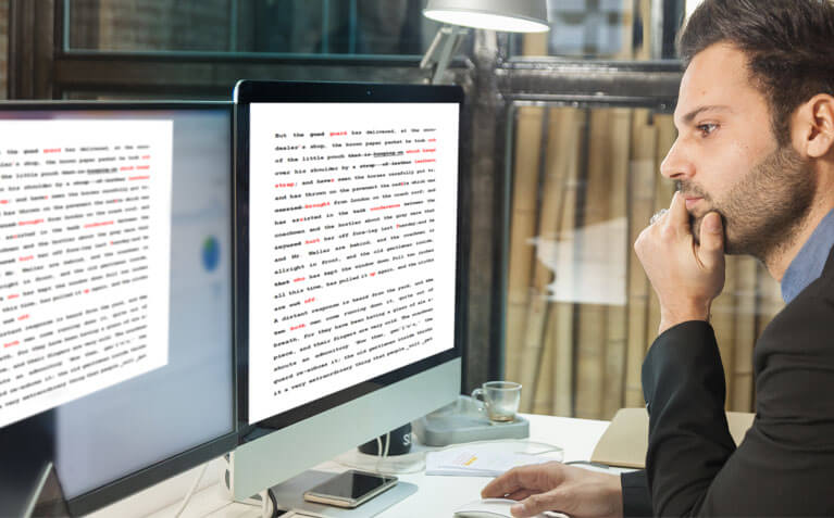 Author reviewing manuscript edits on dual computer monitors