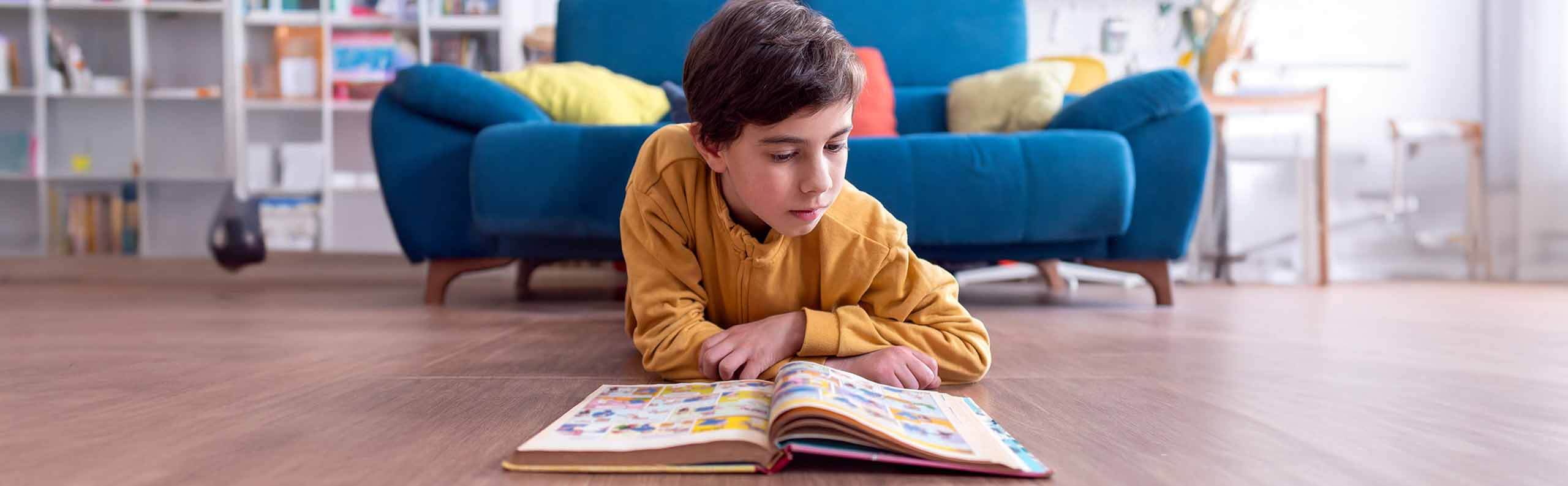 Young boy reading a comic book on the floor