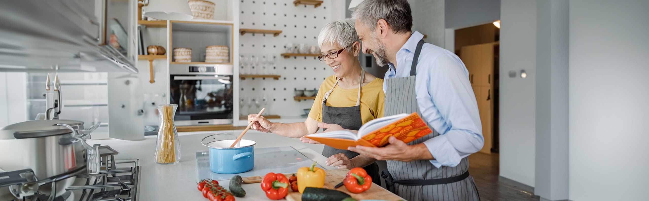 Two people referring to a cookbook while cooking