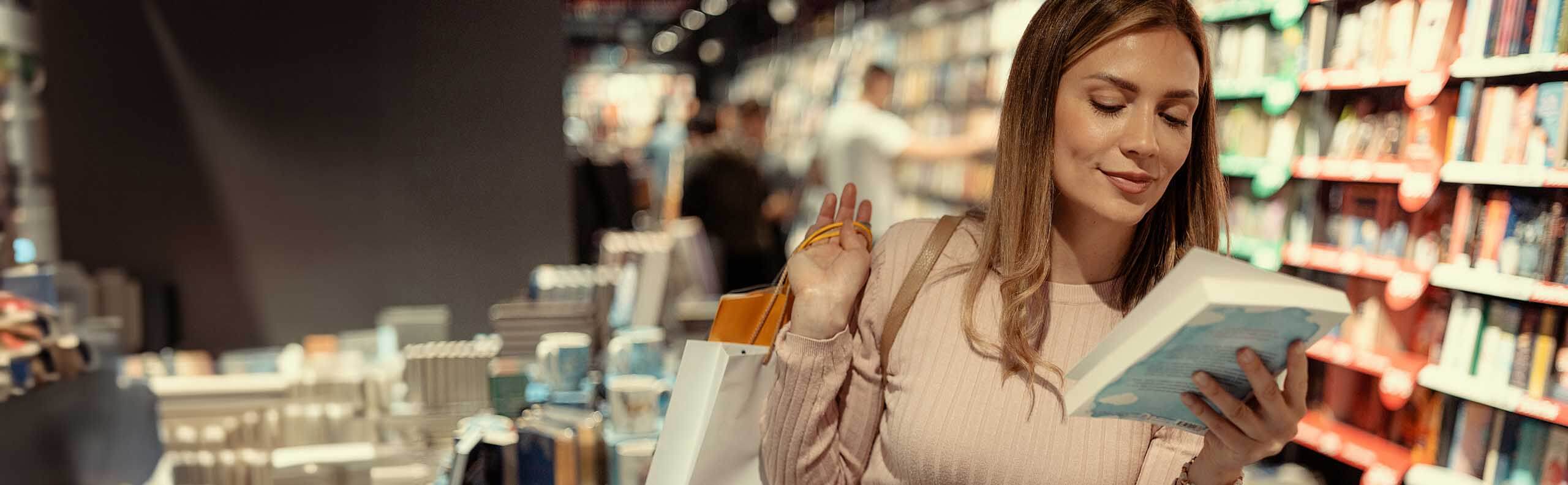 A woman looking at a fiction book in a bookstore