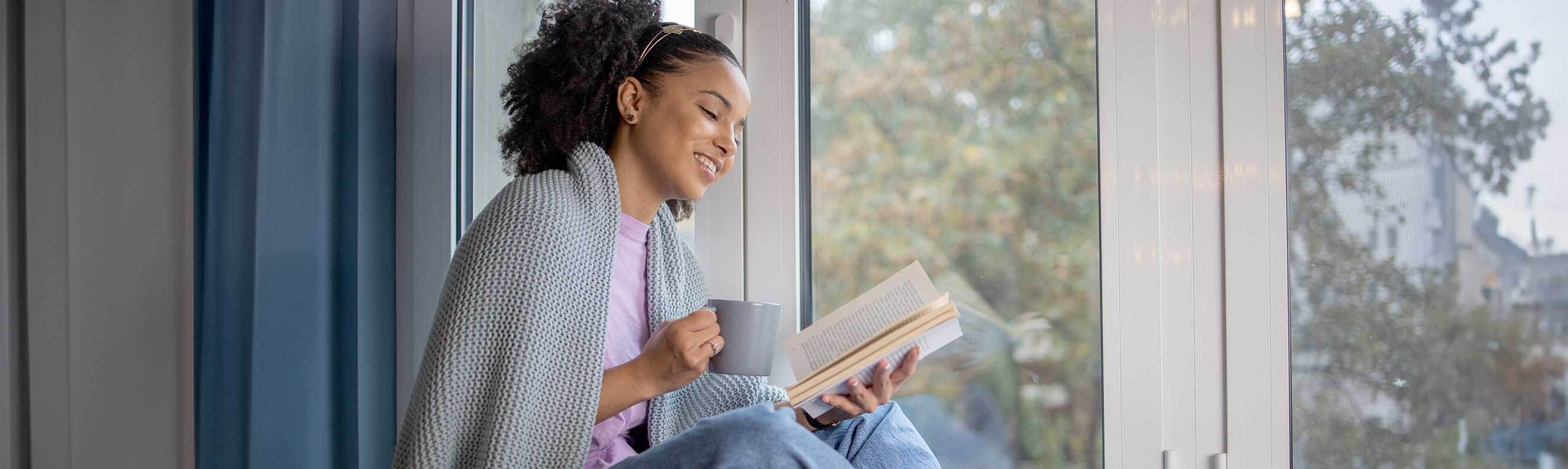 Woman drinking from a mug and reading a self-help book